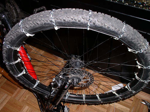 DIY bike tire chains installed on mountain bike wheel showing chain segments secured with cables and zip ties