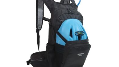 Black lightweight cycling backpack with padded shoulder straps, front helmet holder carrying a blue bike helmet, and hydration tube, designed as the best backpack for bike commuting with compact storage and reflective detailing.