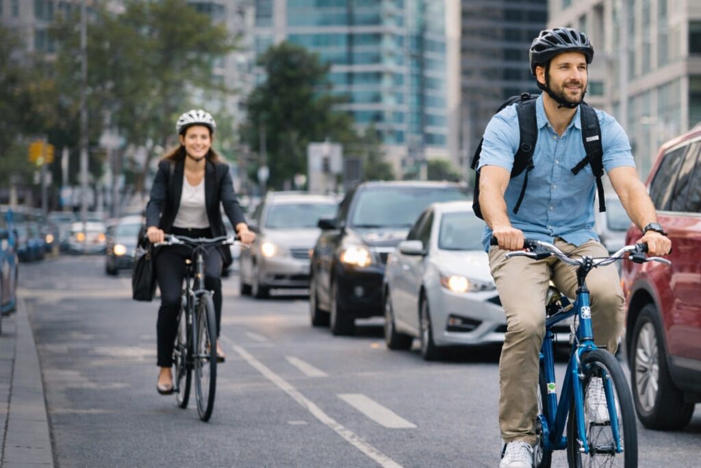 Two bike commuters riding confidently through city traffic, demonstrating real-world fuel savings and daily riding benefits highlighted by the gas saving calculator.
