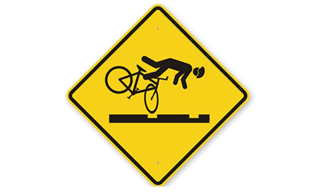 Bicycle-specific track warning sign warning that tracks may catch bike tires, an example of local cycling safety signs